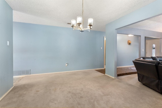 carpeted living area with a textured ceiling, baseboards, visible vents, and a chandelier