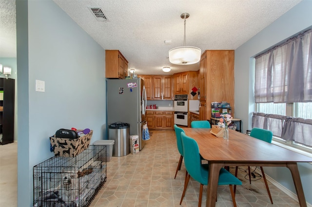 dining area with light tile patterned floors, visible vents, and a textured ceiling