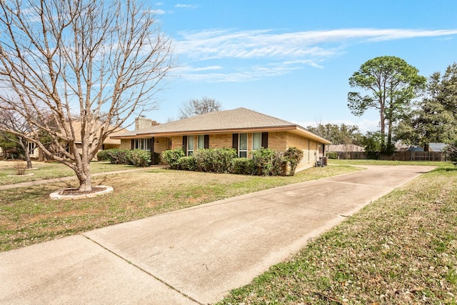 ranch-style home featuring a front lawn, fence, brick siding, and a chimney