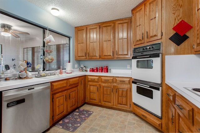 kitchen featuring a sink, light countertops, white double oven, dishwasher, and brown cabinets