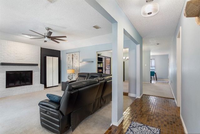 carpeted living room with visible vents, baseboards, ceiling fan, a fireplace, and a textured ceiling