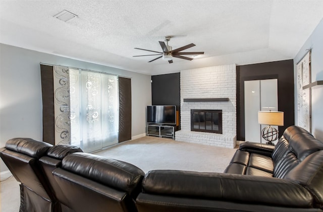 carpeted living room with visible vents, a textured ceiling, ceiling fan, and a fireplace