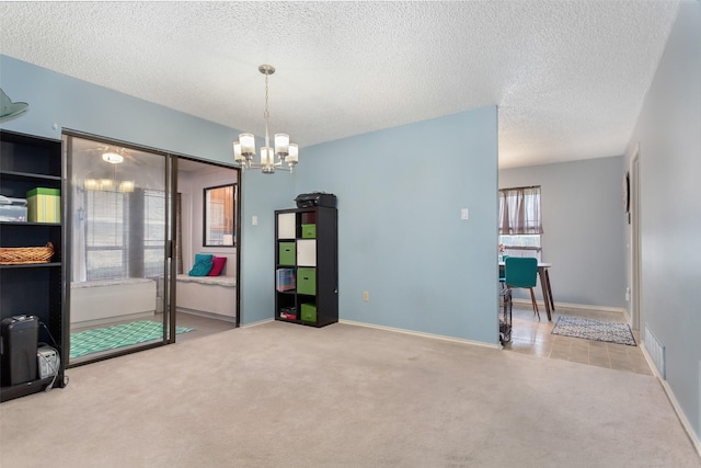 spare room with a notable chandelier, carpet flooring, a textured ceiling, and visible vents