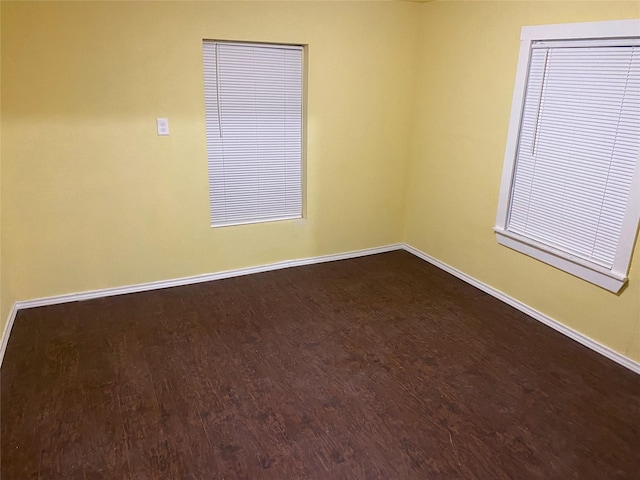 unfurnished room with dark wood finished floors and baseboards