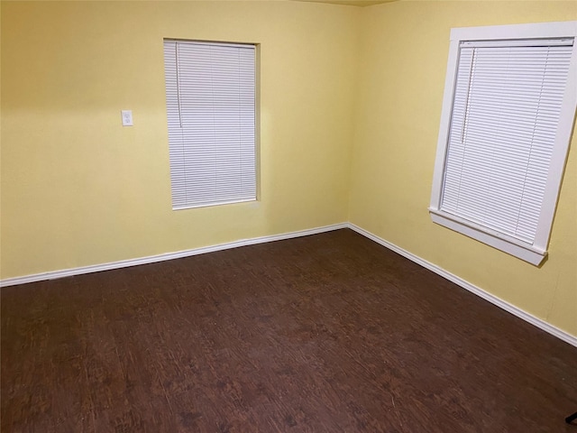 empty room featuring dark wood finished floors and baseboards