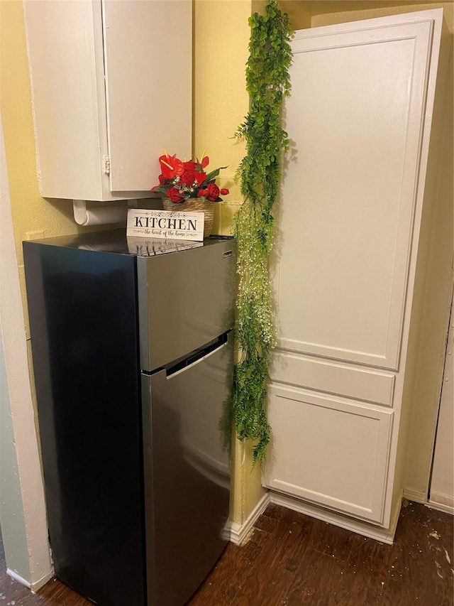 interior details with white cabinetry, dark wood-style flooring, and freestanding refrigerator