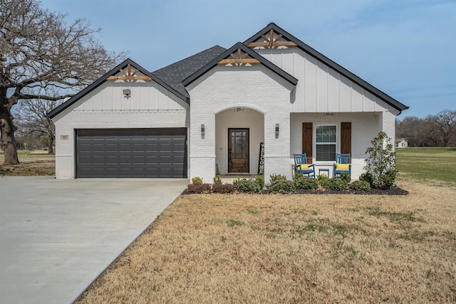 view of front of house with concrete driveway, covered porch, brick siding, and a front lawn