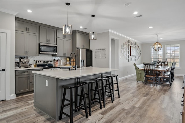 kitchen with gray cabinets, appliances with stainless steel finishes, ornamental molding, and a sink