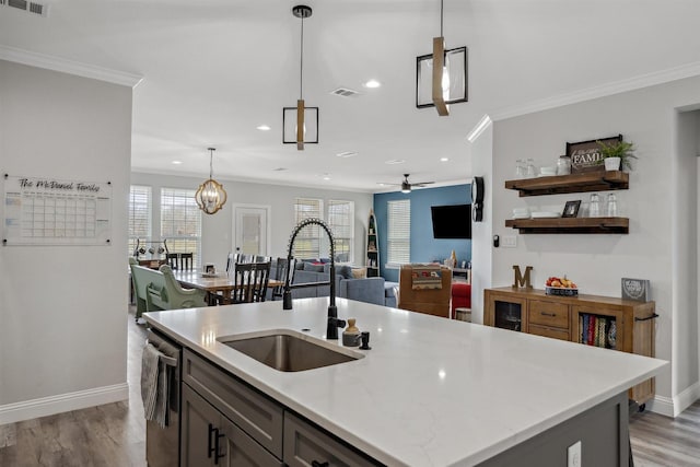 kitchen with visible vents, crown molding, light wood-type flooring, stainless steel dishwasher, and a sink