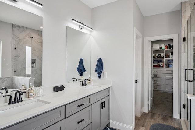 bathroom with a sink, a marble finish shower, and wood finished floors