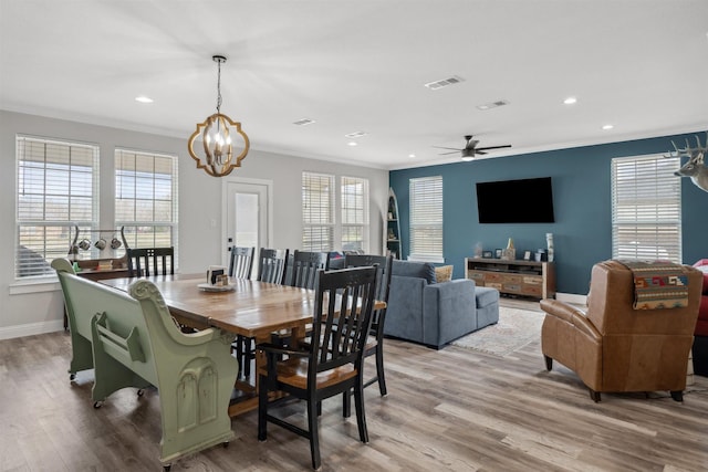 dining room featuring a healthy amount of sunlight, light wood-style floors, visible vents, and ornamental molding