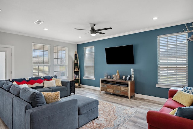 living room featuring a wealth of natural light, visible vents, wood finished floors, and ornamental molding