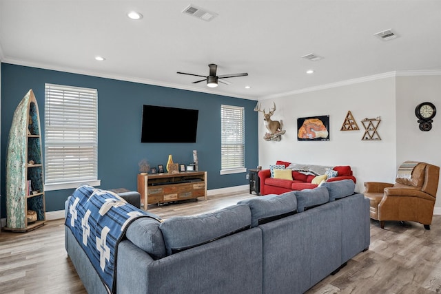 living area with wood finished floors, visible vents, and ornamental molding