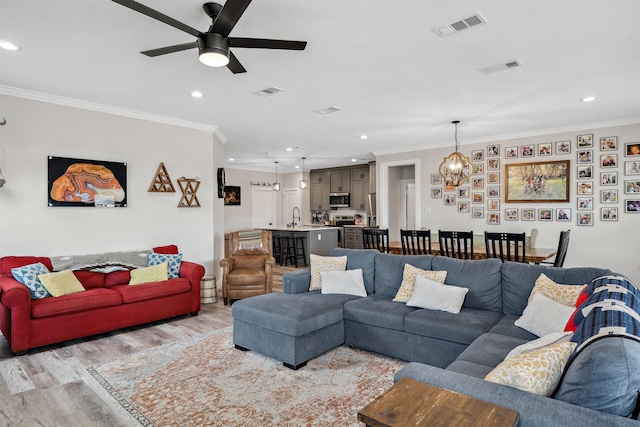 living area featuring visible vents, recessed lighting, crown molding, and light wood-style floors