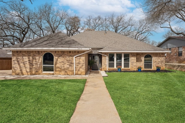 view of front of property featuring brick siding, a shingled roof, a front yard, and fence