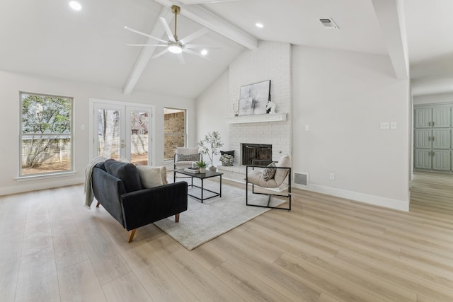 living area with visible vents, ceiling fan, beam ceiling, light wood-style flooring, and a fireplace