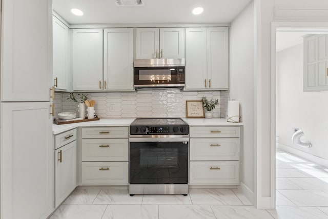 kitchen with range with electric cooktop, marble finish floor, stainless steel microwave, light countertops, and decorative backsplash