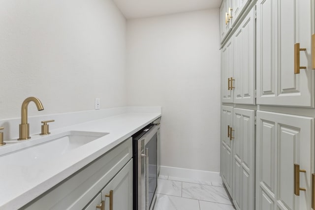 laundry room with wine cooler, baseboards, marble finish floor, and a sink