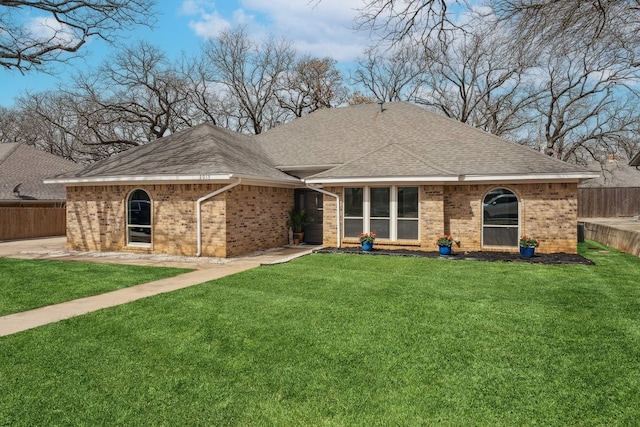 view of front facade featuring brick siding, a front lawn, and fence