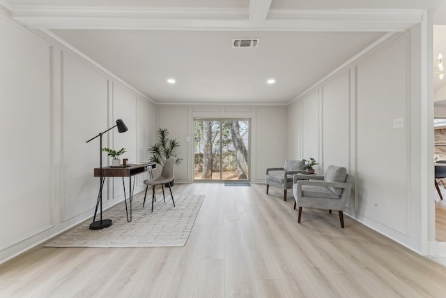 living area with a decorative wall, light wood-type flooring, and visible vents