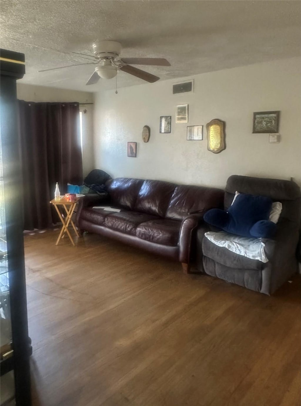 living room with a textured ceiling, wood finished floors, and a ceiling fan