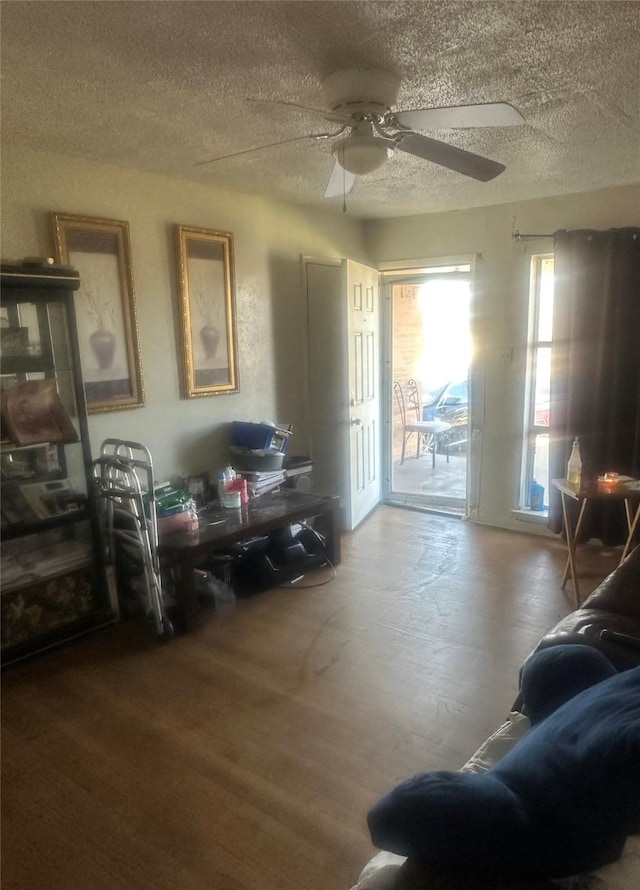 interior space with ceiling fan, a textured ceiling, and wood finished floors