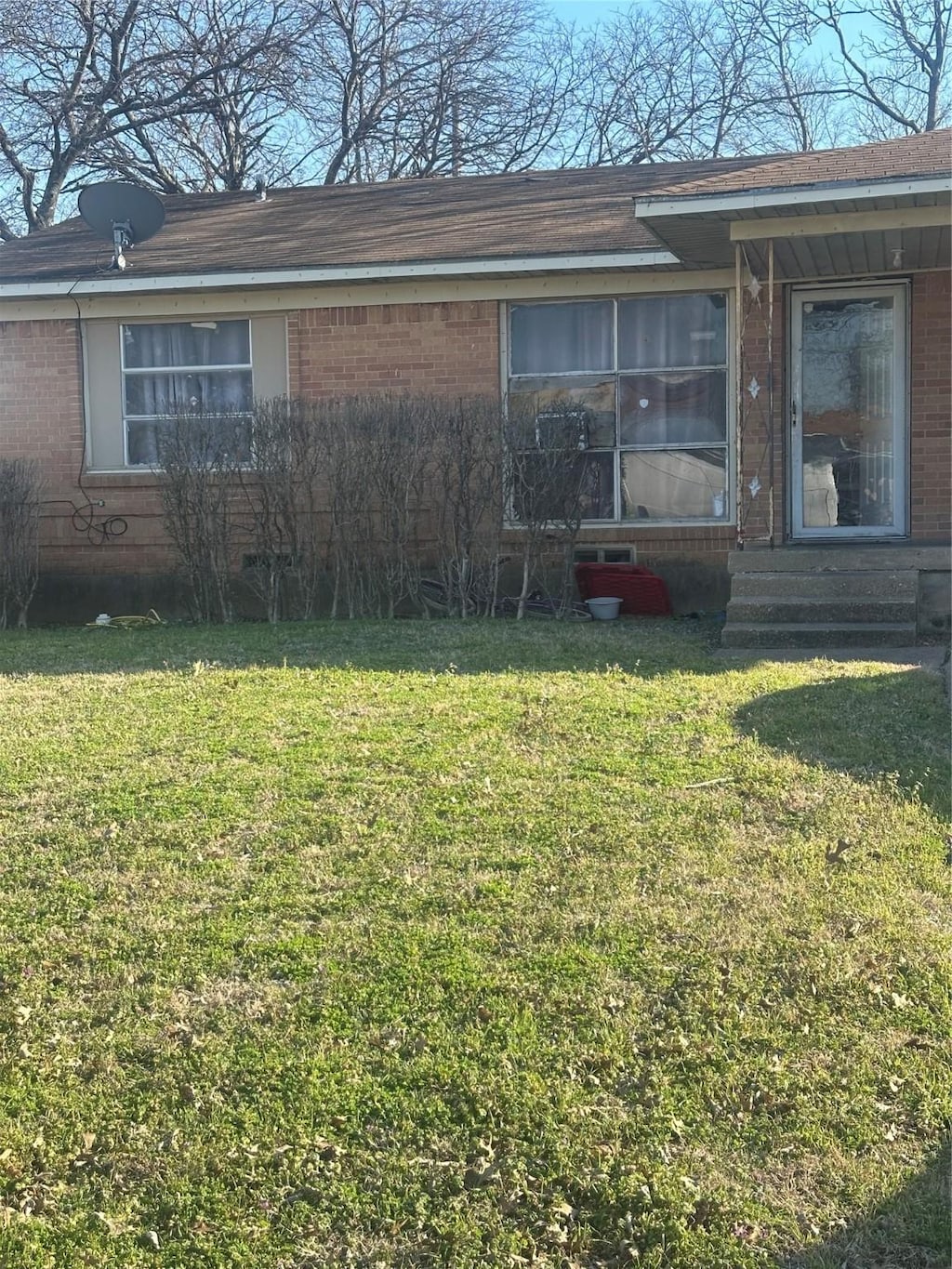 exterior space featuring brick siding, entry steps, and a front yard