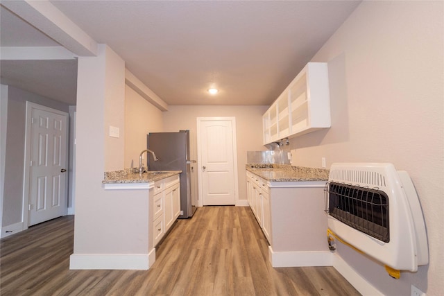 kitchen featuring white cabinets, heating unit, light wood finished floors, and light stone counters