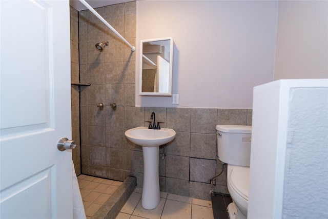 full bathroom with tile walls, toilet, tile patterned floors, and a tile shower