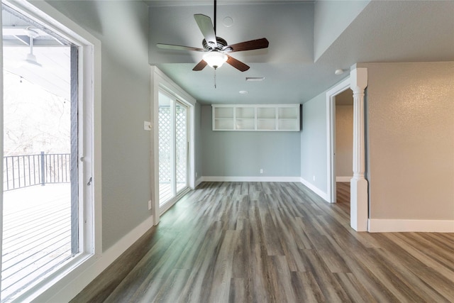 interior space featuring decorative columns, wood finished floors, baseboards, and ceiling fan