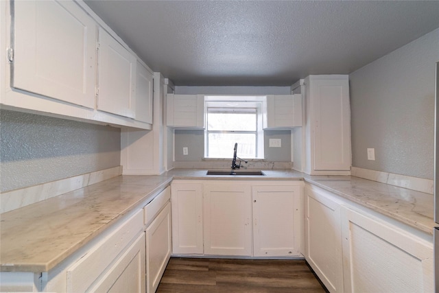 kitchen featuring a sink, a textured ceiling, white cabinets, and dark wood finished floors