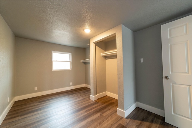 unfurnished bedroom with dark wood-style floors, baseboards, and a textured ceiling