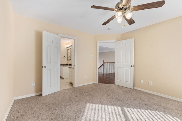 unfurnished bedroom with ceiling fan, baseboards, light carpet, and connected bathroom