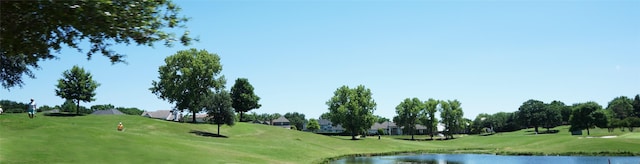 view of home's community with a lawn, view of golf course, and a water view