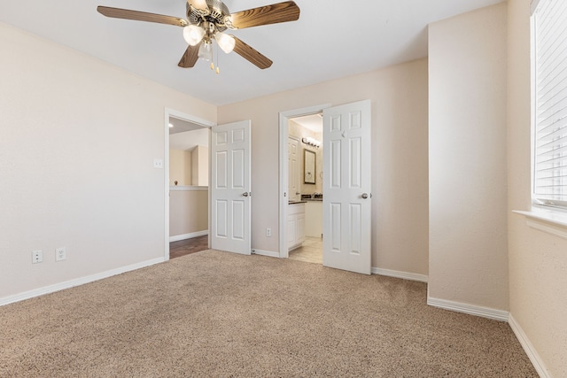 unfurnished bedroom featuring light carpet, ceiling fan, ensuite bathroom, and baseboards