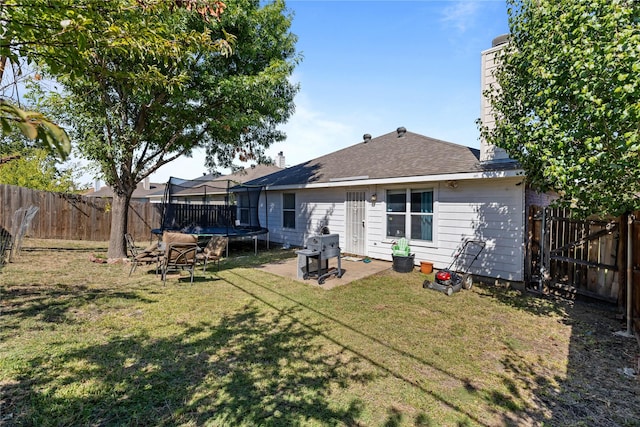 back of property featuring a fenced backyard, a patio area, a lawn, and a trampoline