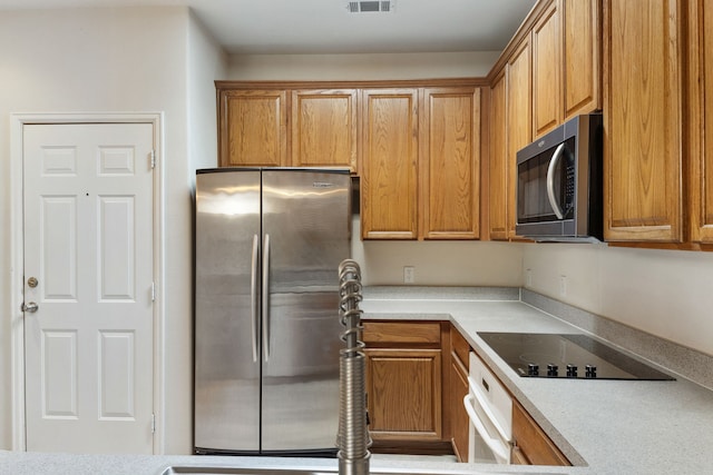 kitchen featuring visible vents, brown cabinets, appliances with stainless steel finishes, and light countertops