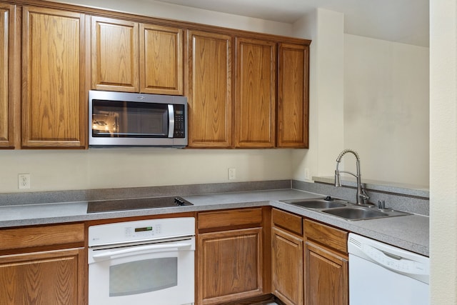 kitchen featuring brown cabinets, white appliances, and a sink