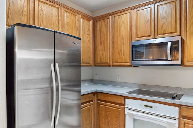 kitchen with stainless steel appliances, brown cabinets, built in study area, and light countertops