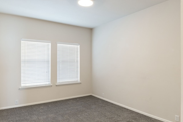 empty room featuring dark carpet and baseboards