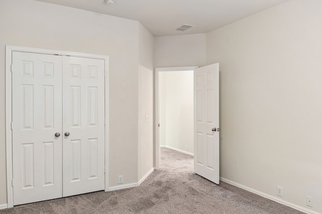 unfurnished bedroom featuring a closet, baseboards, visible vents, and carpet floors