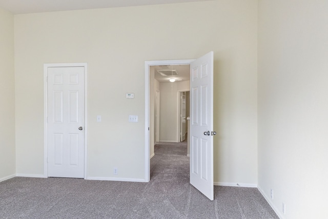 unfurnished bedroom featuring baseboards, visible vents, carpet floors, and attic access