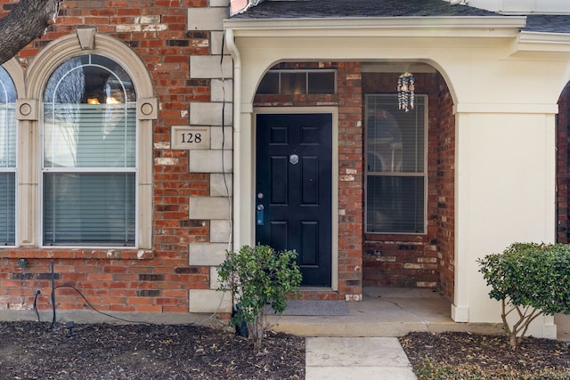 property entrance with brick siding and roof with shingles