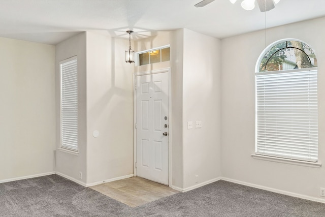 carpeted entryway featuring baseboards and a ceiling fan