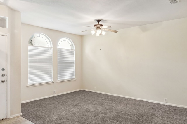 carpeted empty room featuring a ceiling fan and baseboards