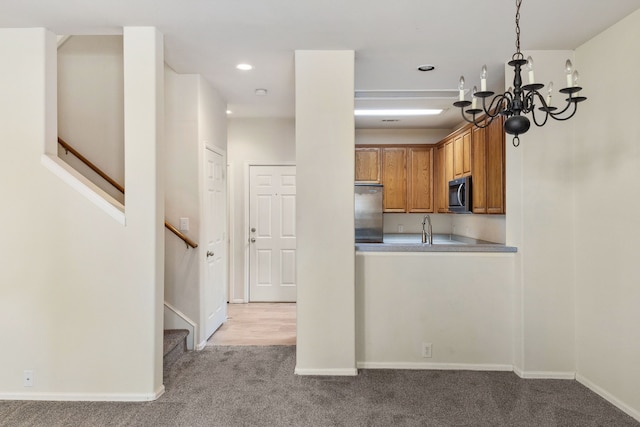 kitchen with baseboards, a chandelier, light colored carpet, brown cabinets, and stainless steel appliances