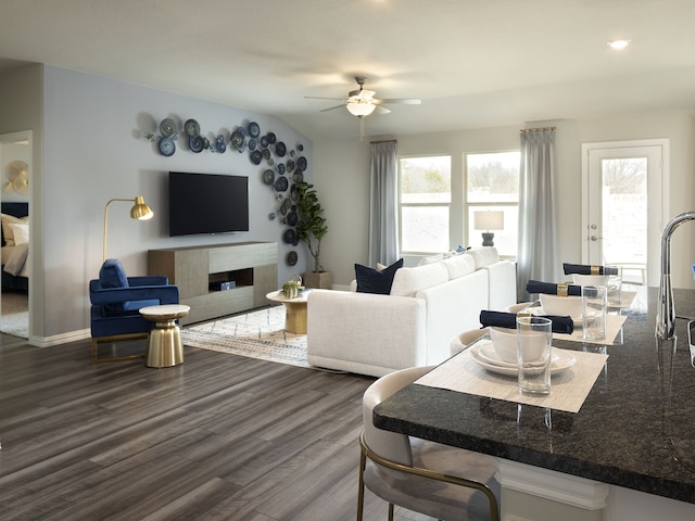 living area with dark wood-type flooring, baseboards, and ceiling fan