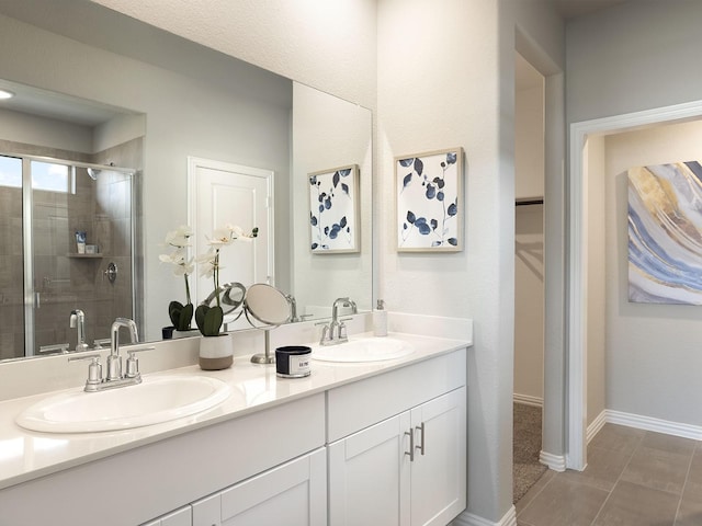 full bathroom featuring double vanity, baseboards, a stall shower, and a sink