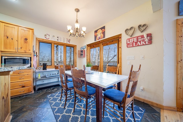 dining area with baseboards, a chandelier, and stone tile flooring