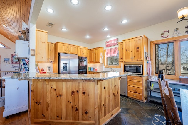 kitchen with a breakfast bar area, light stone counters, visible vents, a peninsula, and appliances with stainless steel finishes